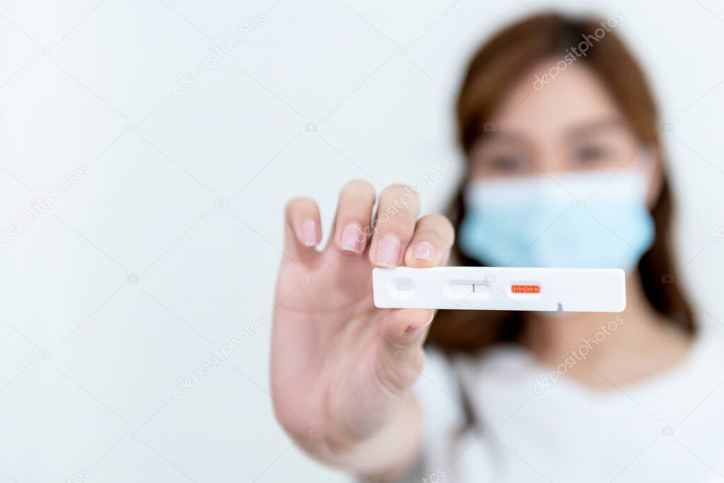 Blurred images of Woman showing test results of Rapid Antigen test COVID-19, showing no infection, On white backgroulnd, to people health care and self-testing for COVID-19 concept.
