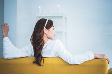 Asyalı bir kadının portre resimleri, çekici ve genç, sarı koltukta oturan, rahatlayan ve beyaz arka planda mutlu olan, insanlara ve rahatlama konseptine.