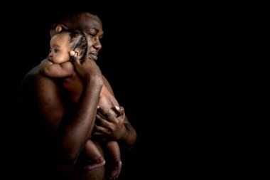 Afrikalı bir babanın, yeni doğmuş bebeğini babasının omzunda, siyah ve koyu arka planda, yeni doğmuş bebek ve Afrikalı aile kavramına sarılışının portresi.