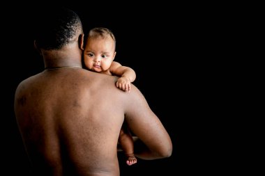 Afrikalı yeni doğmuş bir bebeğin portresi. Babasının siyah arka planda, yeni doğmuş bir bebek ve Afrikalı bir aile kavramına tutunduğu bir omuz.