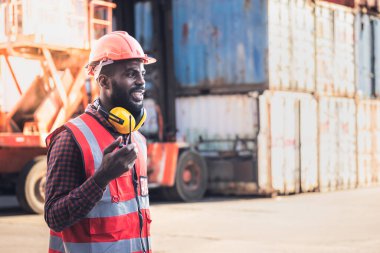 African American workers man, working in containers industry, logistic transport Import-Export Cargo, to business shipping and storage port terminal concept.