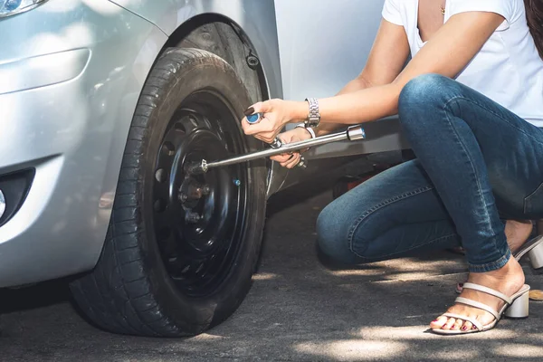 タイヤ交換のための装置であるレンチを使う女車を交換するための装置道路上だけでも 強い女性と交通概念へ — ストック写真