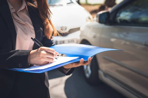 女性は保険代理店が事故車事故報告書を書いていることを通知する人々と交通保険の概念に — ストック写真