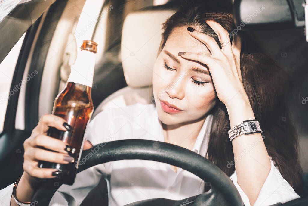 Asian woman driving in a drunken state as a result of drinking alcohol, concept to drinking alcohol while driving it is the cause of accidents on the road.