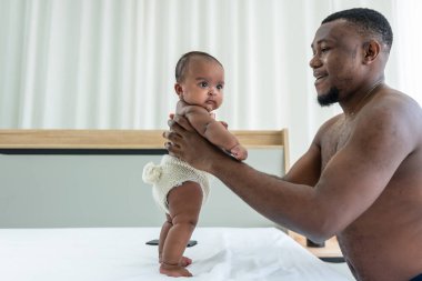 Afrika kökenli Amerikalı bir baba, elinde 3 aylık kızını tutarak beyaz yatakta Afrika kökenli Amerikalı bir aile ve yeni doğan bebek kavramı ile ilişki kurmaya çalışıyor..