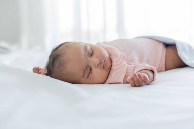 Afrikalı bir bebek beyaz bir yatakta uyuyor ve yatıyor, Afrikalı çocuk kavramına göre..