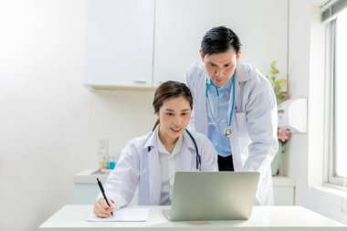 Asyalı doktor erkek ve kadın birlikte çalışarak hasta bilgilerini inceleyerek ve hastanın semptomlarını analiz ederek, hastalara, insanlara ve sağlık hizmetleri konseptine.