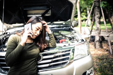 Asyalı çekici bir kadın yardım istemek için cep telefonu kullanıyor, çünkü kamyoneti bozulmuştu, yolculuk sırasında, insanlara ve ulaşım konseptine..