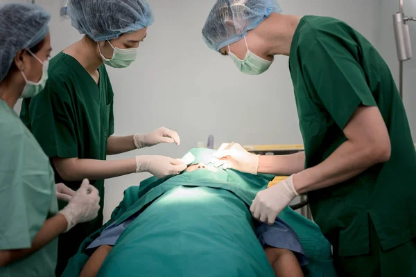 Asian doctor surgeon team,  Working in the operating room, Doing nose surgery on a female patients, to people health care and cosmetic surgery concept.