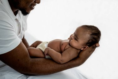 Afrikalı Amerikalı yeni doğmuş bebek 3 aylık, babasının avucunda yatıyor, beyaz arka planda, aile ve yeni doğan konseptiyle.