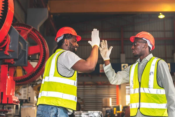 2 male worker African American, working in a factory, Shaking hands and happy that the work done together is successful, concept to teamwork of workers in industrial factories.