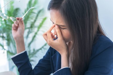 Business woman is using fingers to squeeze the eye area, due to wearing glasses, using the eyes and tried to work for a long time, to working hard and health concept.