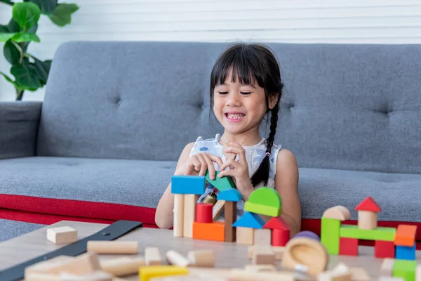 A 5 year old Asian girl is sitting, imagination and paying  the wooden block toy, which is a toy that supports the development of children, to Asian girl and education concept.