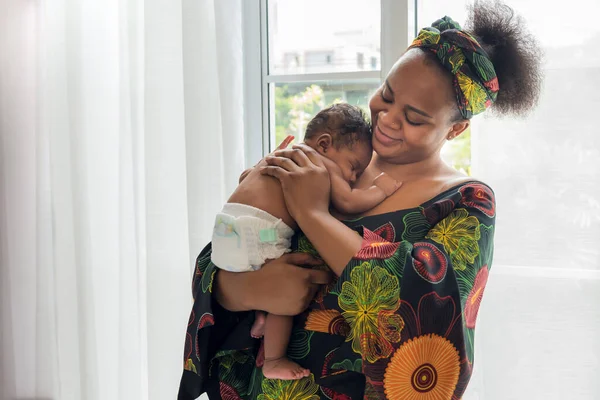 African mother smile and holding a 2-month-old baby newborn son who is sleeping happily on his mother's chest, to relationship in African family and baby newborn concept.