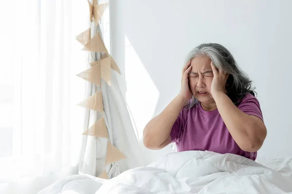 Ασιάτισσα Ηλικιωμένη Γυναίκα Που Κάθεται Στο Λευκό Κρεβάτι Έχοντας Πονοκέφαλο — Φωτογραφία Αρχείου