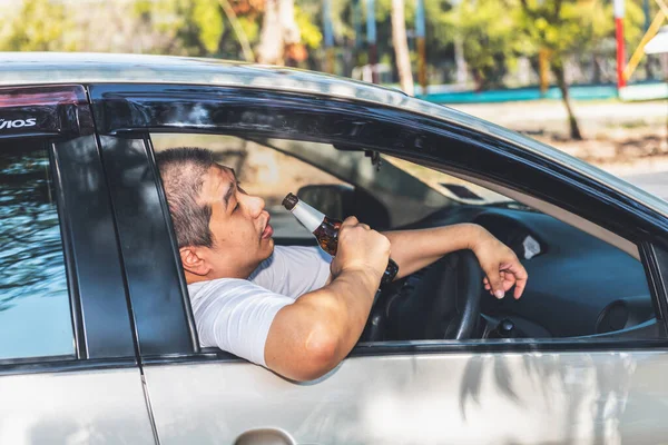 運転中はアジア系の中年男性が酒を飲んで酔いしれる 交通事故の原因についての考え方です — ストック写真