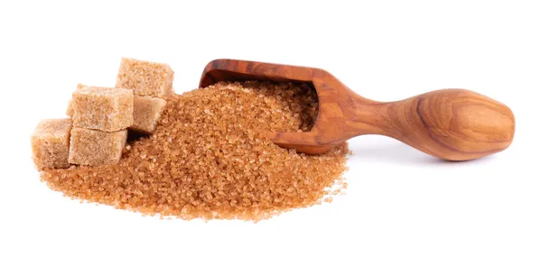 Коричневый сахар в деревянной сковороде, изолированный на белом фоне. Куча кристаллов сахарного тростника и кубиков сахара. — стоковое фото