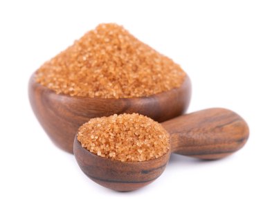 Tahta kasede esmer şeker ve beyaz arka planda izole edilmiş kaşık. Baston şeker kristalleri yığını.