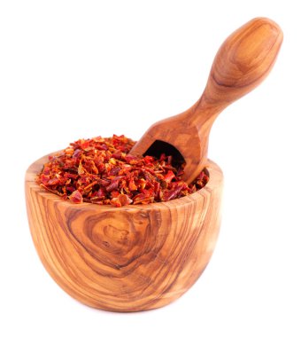 Kırmızı kırmızı biber taneleri zeytin kabında ve kepçeyle kaplanmış, beyaz arka planda izole edilmiş. Baharatlar ve bitkiler