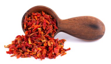 Tahta kaşıkta kırmızı biber taneleri, beyaz arka planda izole edilmiş. Baharatlar ve bitkiler