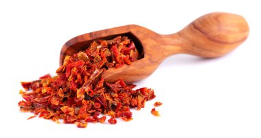 Beyaz arka planda izole edilmiş zeytin kepçesinde kurutulmuş kırmızı biber taneleri. Baharatlar ve bitkiler