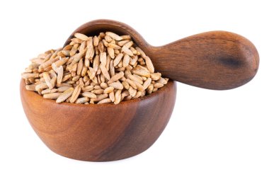 Beyaz arka planda izole edilmiş çavdar taneleri. Ahşap kasede ve kaşıkta çavdar tohumu tohumu. Kuru çavdar taneleri.