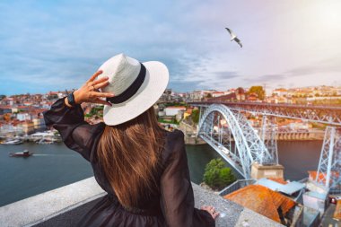 Porto şehrinin güzel manzarasının tadını çıkaran genç bir turist ve gün batımında ünlü I. Dom Luis Köprüsü. Kuzey Portekiz 'de yaz tatili.