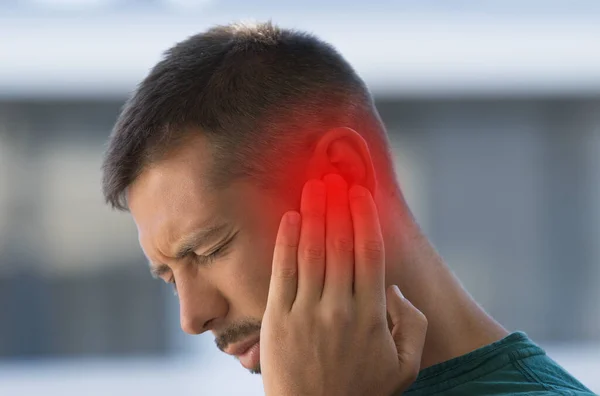 Мужчина, страдающий от сильной боли в ушах или ухе. Воспаление ушей, отит или звон в ушах — стоковое фото