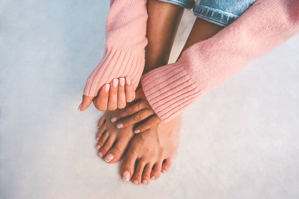 Mujer con estilo en suéter rosa mostrando sus hermosas uñas con manicura francesa y pedicura. Uñas después del tratamiento de manicura y pedicura. Copiar espacio — Foto de Stock