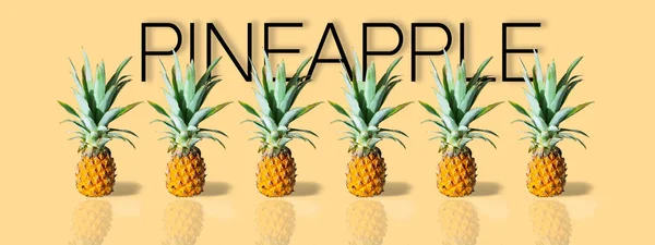 Färska mogna ananas i rad isolerad på gul bakgrund. Exotisk tropisk frukt. Banderoll — Stockfoto