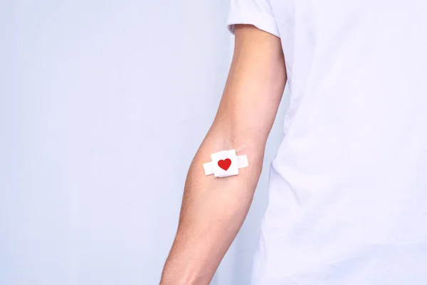 Blood donation. Blood donor with bandage after giving blood on a white background. Copy space — Stock Photo, Image