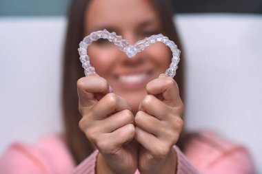 Woman with perfect smile after invisible invisalign aligners treatment clipart