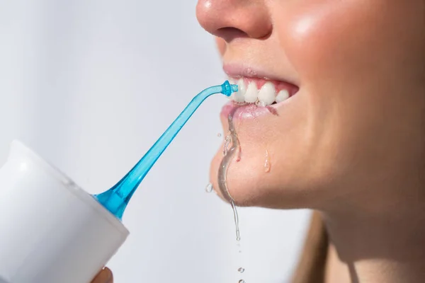 Wanita dengan senyum putih yang sempurna menggunakan flosser air portabel atau iririgator oral — Stok Foto