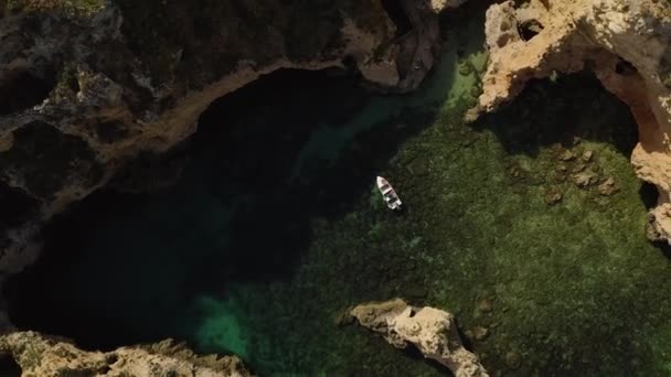 Pandangan atas udara kapal wisata di Atlantik laut dengan air hijau dan tebing batu di Ponta da Piedade, Algarve, Portugal Stok Rekaman Bebas Royalti