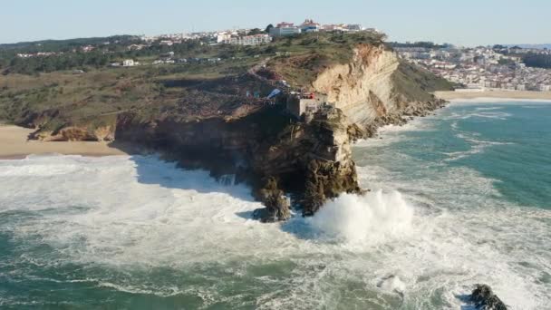Pandangan pesawat tak berawak dari gelombang laut Atlantik yang kuat dan pantai tebing di Nazare, Portugal Stok Video