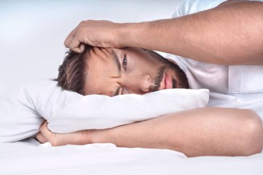 Yatakta yastığın üzerinde yatan depresif hastalıklı bir adam. Kötü düşünceleri olan depresif bir adam.