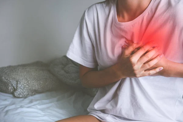 Woman holding chest because of acute heart pain or chest pain. Heart disease and heart attack symptom — Stock Photo, Image