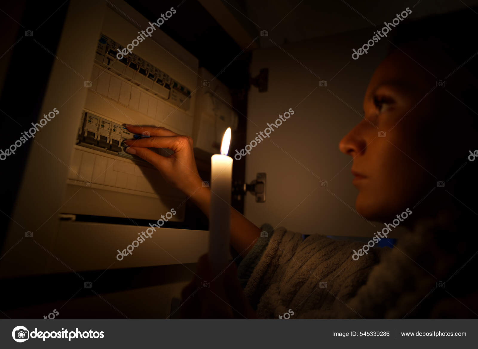 Woman in total darkness investigating fuse box at home during power