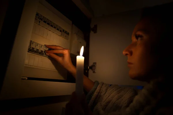Женщина в полной темноте исследует предохранитель дома во время отключения электроэнергии или отключения электричества. Без электричества — стоковое фото