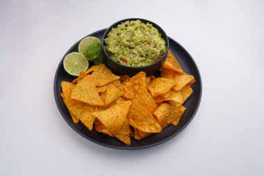 Beyaz arka planda izole edilmiş siyah guacamole sosu, sos ve tortilla cipsi ya da nachos tabağının üst görüntüsü