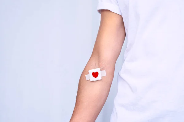 Conceito de doação de sangue com espaço de cópia. Doador de sangue com bandagem depois de dar sangue em um fundo branco — Fotografia de Stock