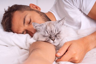 Adam kediyle yatıyor. Güzel kedi ve sahibi. İnsanlar ve hayvanlar arasında sevgi ve güven