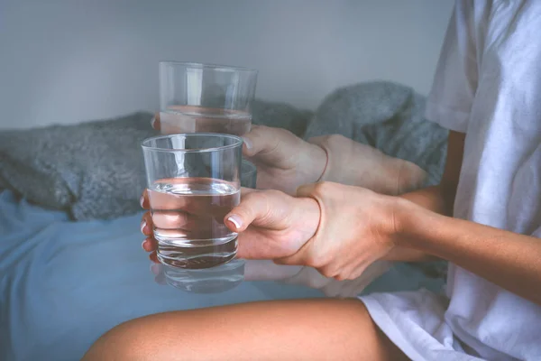 Wanita memegang gelas air di tangan gemetar dan menderita gejala penyakit Parkinson atau getaran esensial. — Stok Foto