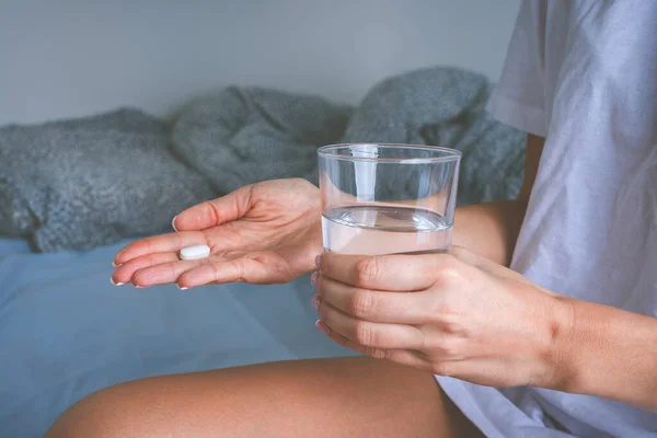 女人拿着一杯静水，从头疼的疼痛中服用止痛药。服用药物或抗抑郁药的妇女 — 图库照片