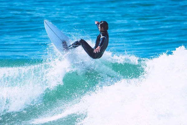 Surfista haciendo truco en la ola en el tablero corto. Hombre cogiendo olas en el océano. Actividades náuticas Imagen de archivo