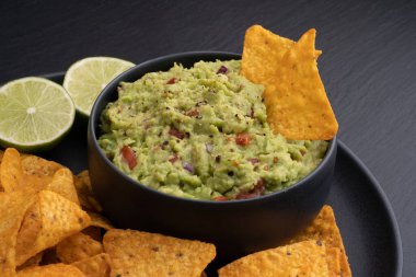 Tortilla cipsli guacamole sosu ya da siyah arka planda cips ve limon. Yüksek kalite fotoğraf