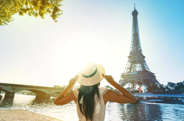 夕暮れ時にパリのエッフェル塔の前に立つ太陽の帽子と白いドレスの若い女性観光客 フランスの旅行 観光の概念 高品質の写真 ストックフォト