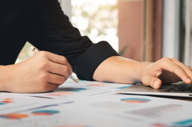 Muhasebe konsepti. Finans satış verilerini ve ekonomik büyüme grafiğini analiz eden bir dizüstü bilgisayar kullanarak çalışan bir iş adamı. Kahve dükkanında..
