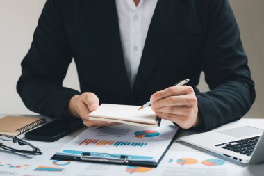 Mali verilerden iş satış performansını analiz eden ve planlayan erkek yöneticiler, finans satış verilerini ve ekonomik büyüme grafiğini analiz etmektedir..