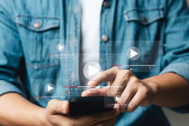 Akıllı telefonlu çevrimiçi film yayını. Genç adam cep telefonundan hayali bir video oynatıcı servisi ile film izliyor..